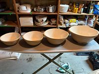 All four ceramic mixing bowls lined up by size on table in basement storage