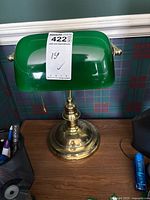 Front view of traditional banker’s lamp showing green glass shade, brass base, pull chain, and size label marking 15 inches tall.