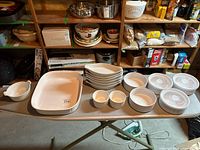 Wide shot showing all white stoneware bakeware and serveware items arranged on a table, including large rectangular baking dish, oval baking dishes, ramekins, and small serving bowls.