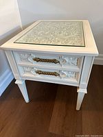 Front and side view showing carved drawer fronts with brass handles, tapered legs, and inset glass top.