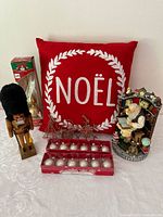 Full lot overview showing nutcracker, resin Santa, red Noel pillow, ornament box, tree topper, and wire ornaments on white surface
