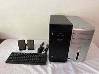 Two desktop computer towers with keyboard, mouse, and speakers on a white surface.