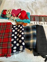 Various folded fabric pieces including plaid, polka dot, and solid materials alongside red felt and decorative ribbons.