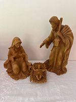 Photo showing full set of three Holy Family statues: Mary kneeling, Joseph standing with staff and birdhouse, and baby Jesus in manger.