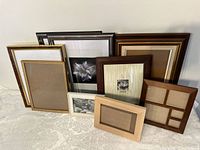 Overview of all 9 frames grouped together on white fabric surface, showing different sizes, finishes and one multi-photo frame.