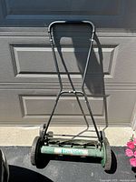 Front view of green Lee Valley push reel lawn mower showing handle, wheels, and cutting reel.