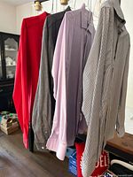 Four men's dress shirts hanging including red, gray, lavender, and patterned white shirt