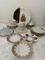 Photo of assorted cups, saucers, and plates arranged on table, showing variety and patterns.