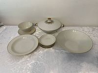 Full set of porcelain serving dishes including bowls and lids with gold rim and floral detailing on lid
