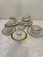 Front view of vintage Thomas Germany porcelain tea and coffee cup set with gold rims, including cups, saucers, creamer, and sugar bowl.