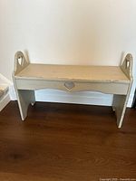 Full view of the wooden bench showing its overall shape, heart cutouts and paint finish.