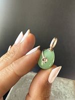Photo showing side angle of the green egg-shaped stone pendant with silver flower detail and loop bail