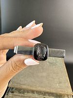 Front view of rectangular sterling silver tie-clip showing dark hematite intaglio carved with profile head.