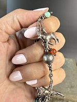 Close-up photo showing the bracelet with a goat charm, large metal beads, and colored beads.