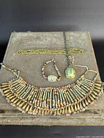 Photo showing the full collection laid out on beige surface including a beaded collar necklace, two other bead necklaces, and a scarab pendant necklace.