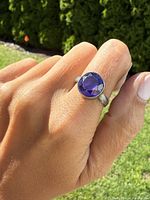 Photo showing the amethyst ring worn on a finger in natural light, highlighting the purple gemstone and silver band details.