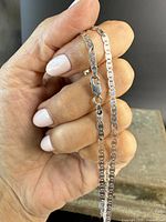 Close-up of the lobster claw clasp and mariner chain links held in hand showing the necklace's detail and clasp mechanism.