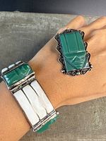 Photo showing bracelet and brooch worn on arm to display size and detail.