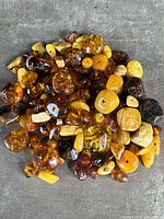 Cluster of natural amber beads on gray fabric showing various colors and drilled holes.