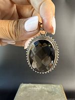 Front view of the large oval faceted smokey quartz set in sterling silver pendant. Decorative beaded bezel surrounds the stone.