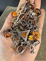 Pile of assorted sterling silver and Baltic amber jewelry in hand