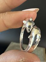 Close-up photo of sterling silver ring showing detailed dolphin heads from the side.