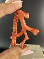 Close-up of the coral branch pendant showing its natural shape, texture, and color held by hand.