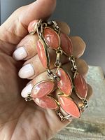 Hand holding the matching bracelet showing the pink marquise stones set in gold overlay around sterling silver.