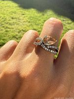 Ring worn on finger showing pear-shaped topaz and clear stone swirl detail under natural light.