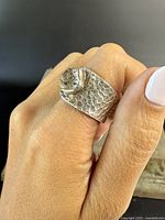 Close-up front view of the silver ring worn on finger showing faceted clear quartz and hammered metal texture.