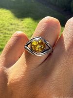 Ring worn on finger in sunlight showing amber stone and silver band
