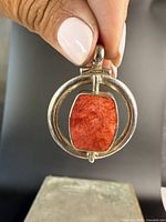 Front view of the pendant showing the coral gemstone inside circular sterling silver frame.