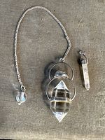 Two sterling silver pendants with clear quartz crystals; one double terminated with circular silver frame and chain, one single quartz point with silver cap.