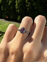 Front view of the ring on finger, showing amethyst oval stone and silver band.