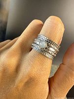 Vintage sterling silver ring with multiple textured and smooth spinning bands worn on finger; round moonstone cabochon centerpiece.