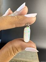 Front view of opal pendant showing iridescent play of color in natural opal and silver bezel setting