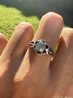 Ring worn on hand, showing front details of aquamarine and silver prong setting