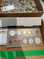 Two plastic holders containing 1967 Centennial coins in a cardboard box