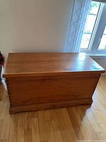 Full view of the antique blanket box showing its rectangular shape, dovetail joinery, and wood grain.