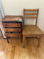 Full view of antique wooden cabinet with drawers partially open showing sewing threads and chair beside it.