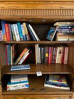 Bookshelf with assorted books in hardcover and paperback, mixed sizes and subjects.