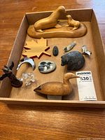 All figurines and collectibles arranged in a box, showing variety of materials and animals including seal, bear, duck, birds, dolphin, and maple leaf