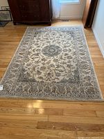 Full view of rug on hardwood floor showing entire medallion pattern and border