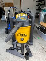 Front view of Dirt Hound 12 gallon wet/dry shop vacuum with hose and attachments laid out in front.