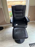 Overall view of the black faux leather recliner chair with matching ottoman included.