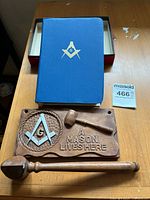Top view of all three items together: blue book, wooden gavel, and wooden plaque with carving and inscription.