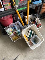 Overview of gardening tools with yellow-handled loppers, plastic buckets, and assorted gardening accessories.