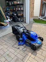 Front-left view of mower with battery, charger, grass bag