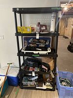 Full view of black plastic shelving unit with various items on shelves, showing size and structure.