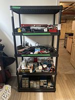 Black plastic shelf filled with various tools and miscellaneous items (contents not included).